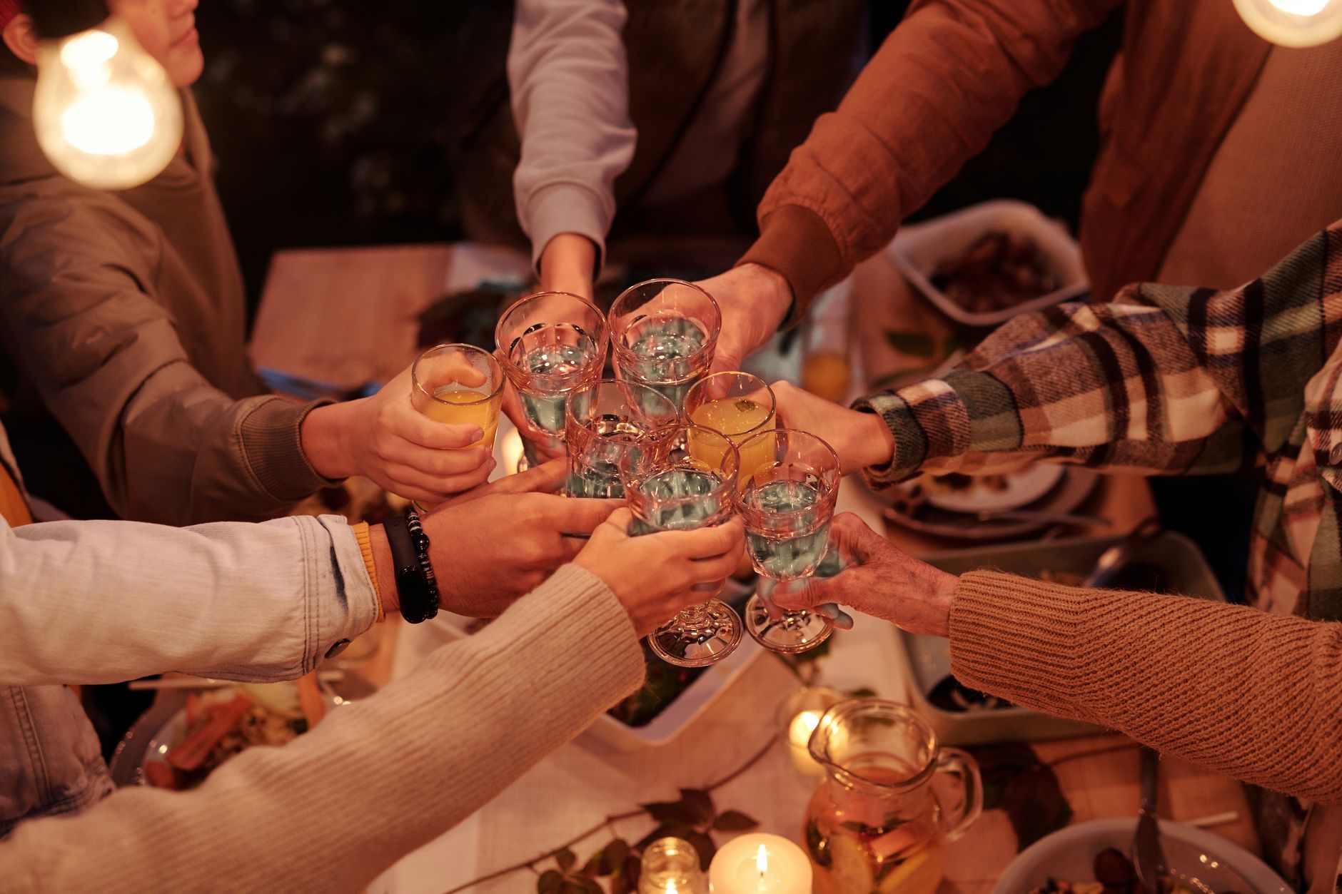 Hands meeting in a toast over a candlelit table