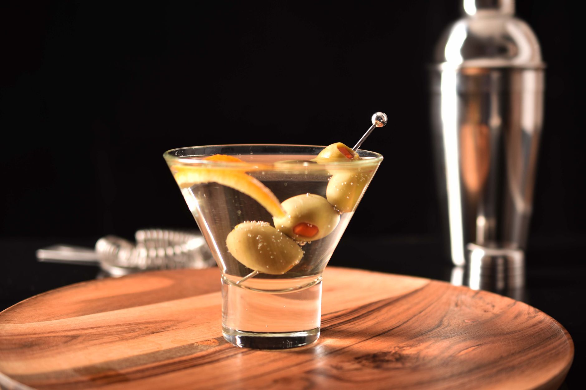 A classic vodka martini served in a chilled glass with olives, on warm wood