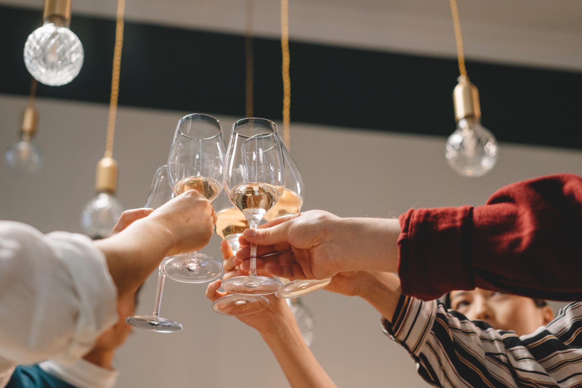 Friends clinking glasses under warm pendant lights